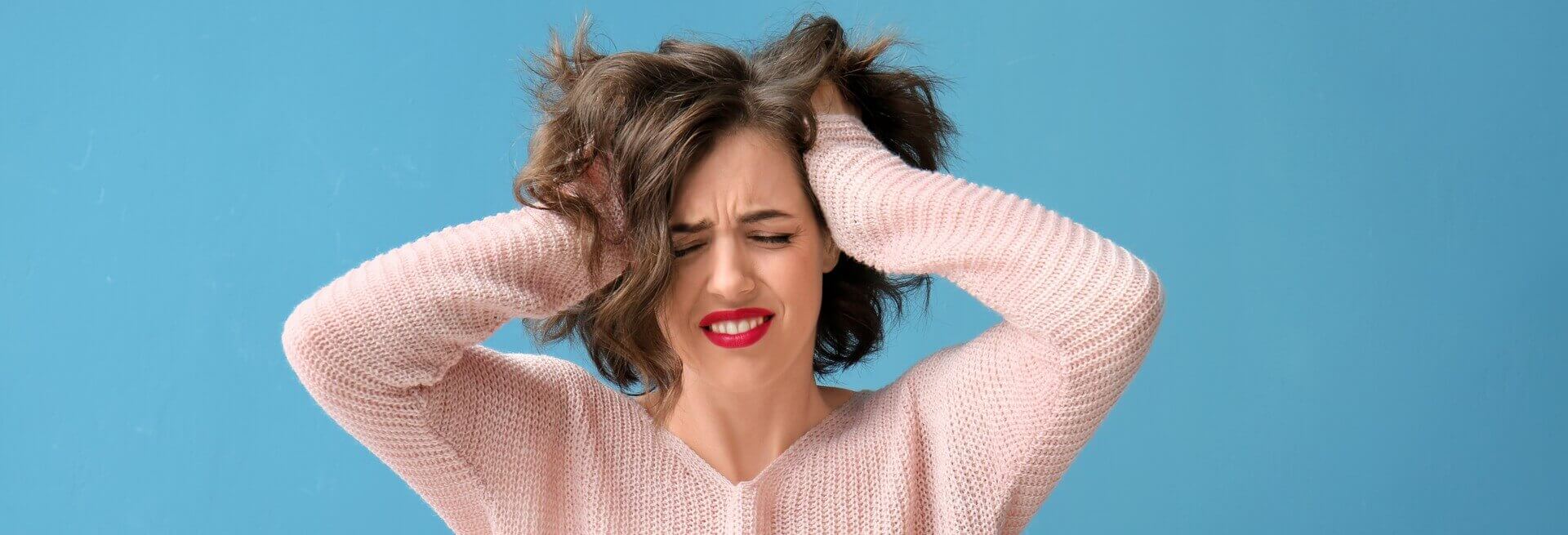Mulher com as duas mãos na cabeça e com feição de estresse