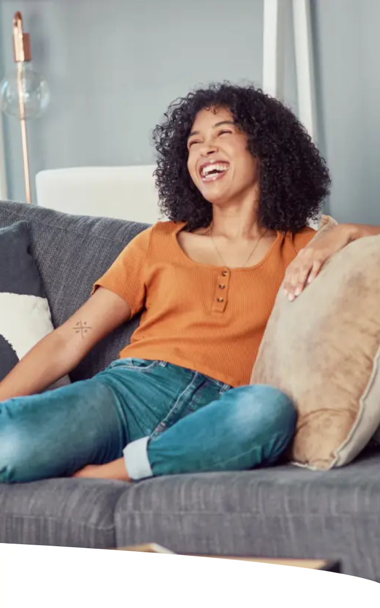 Mulher sentada no sofá de casa sorridente e com aparência saudável