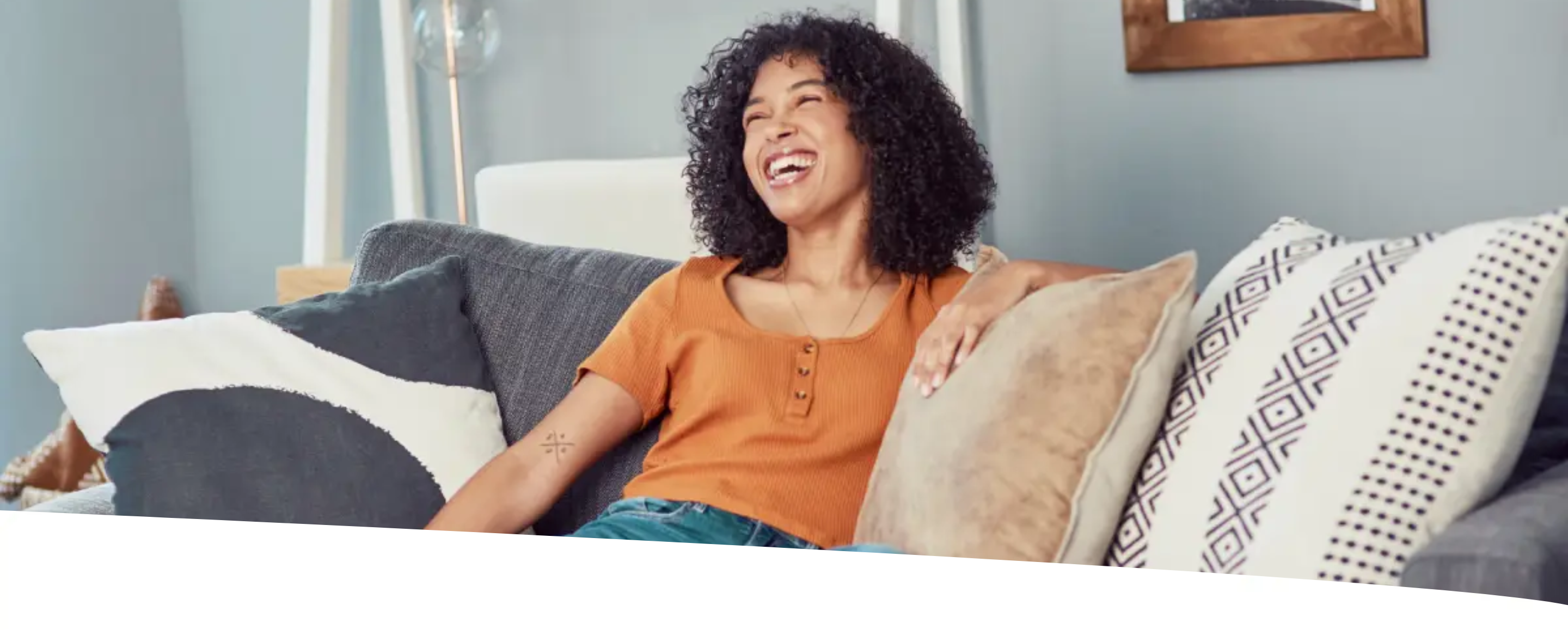 Mulher sentada no sofá de casa sorridente e com aparência saudável