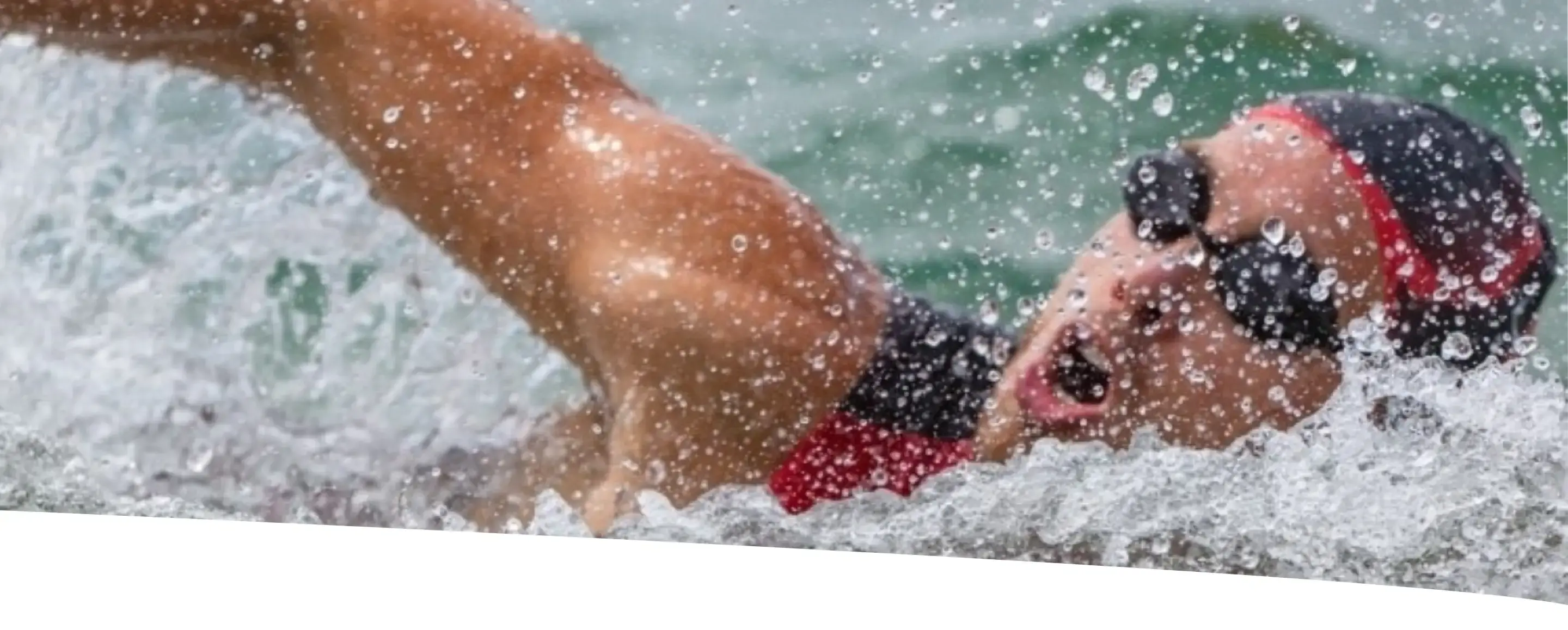 Atleta nadando em mar aberto durante etapa de natação do triatlo Ironman.