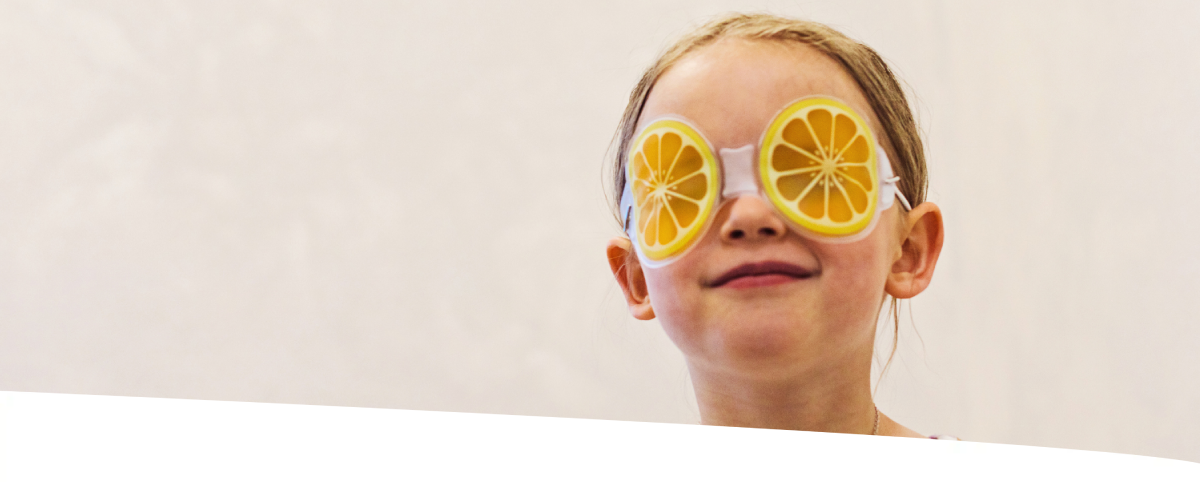 Menina usando uma máscara divertido em formato de rodelas de laranja