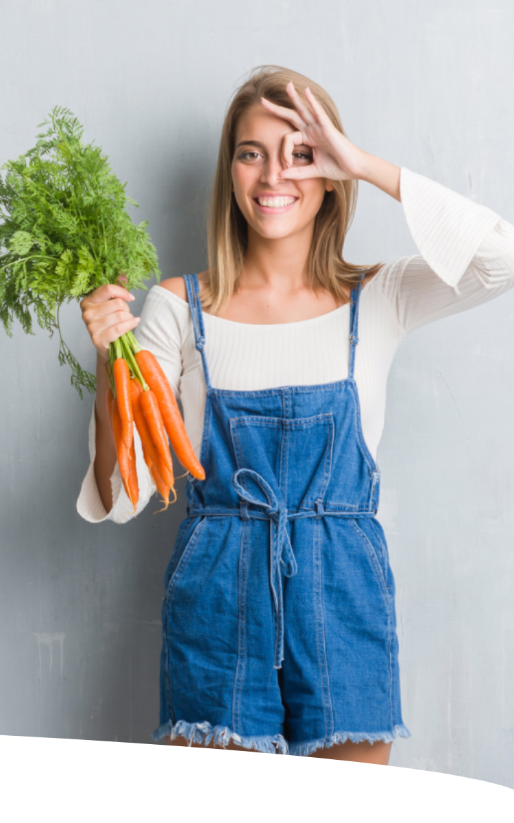 Mulher segurando cenouras pelo talo e destacando o olho com os dedos da outra mão