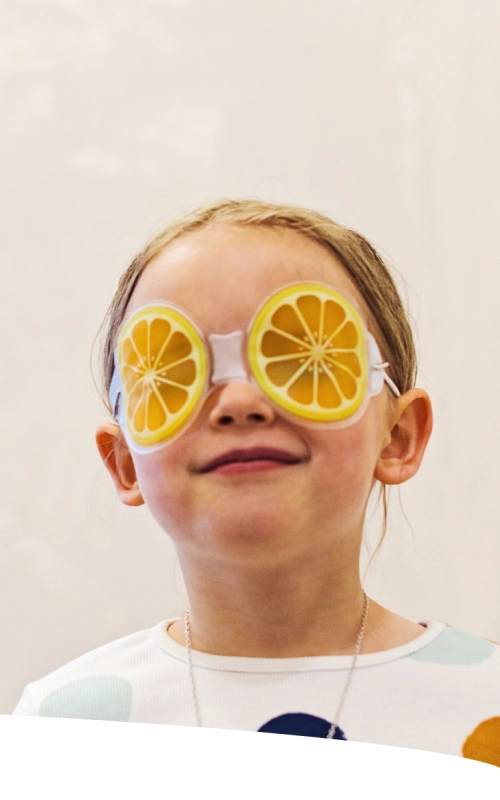 Menina usando uma máscara divertido em formato de rodelas de laranja