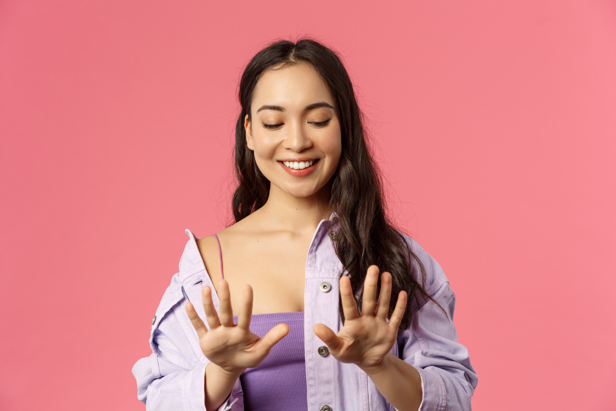 Jovem olhando alegre para suas unhas das mãos.