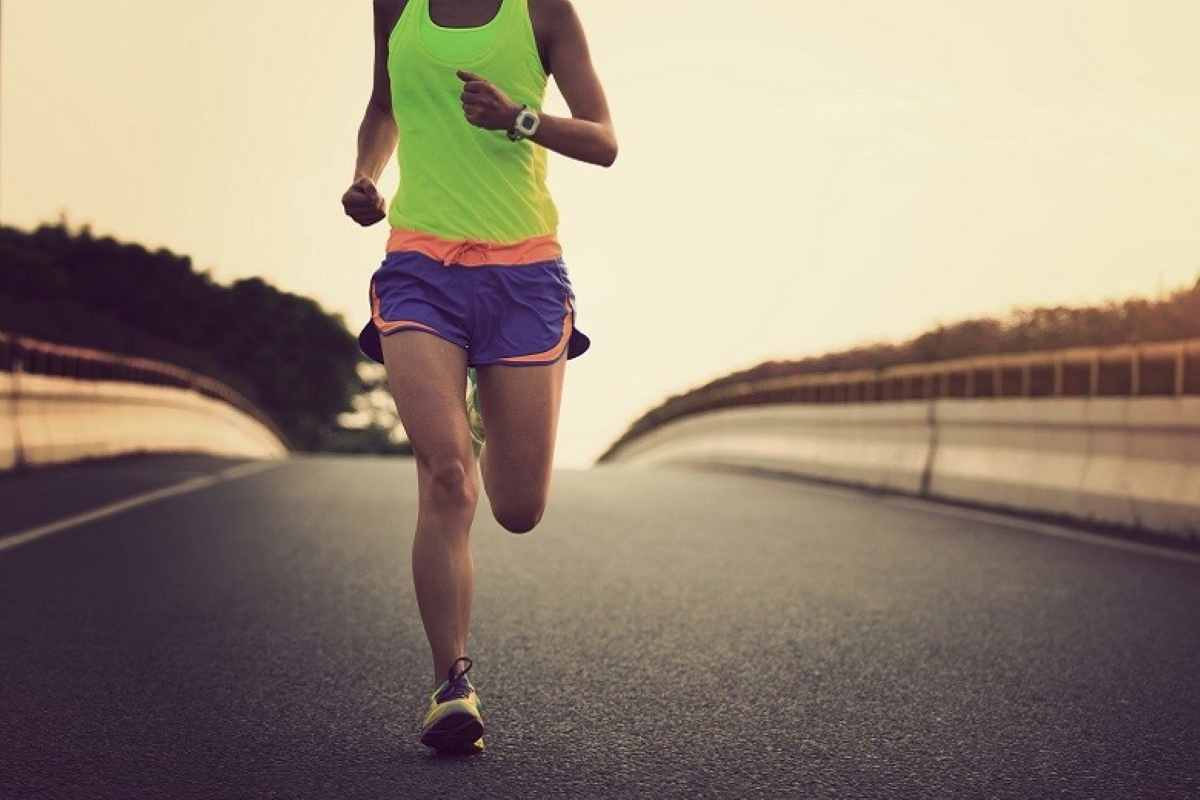Atleta correndo em estrada durante prova de triatlo Ironman, ao amanhecer.