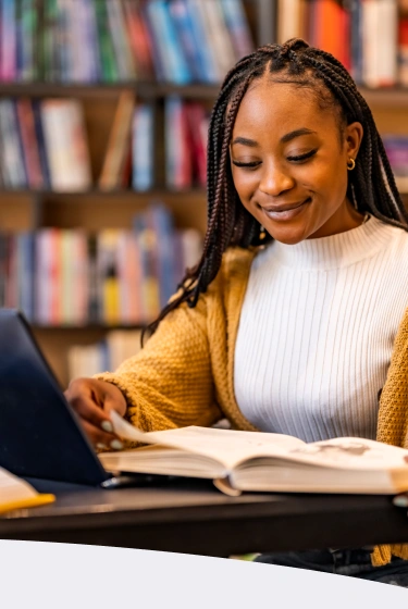 Mulher trabalhando no computador enquanto faz anotações, representando foco, energia e produtividade no dia a dia.
