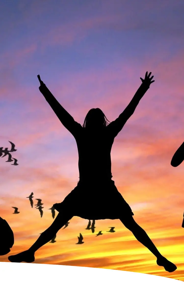 Silhuetas de quatro mulheres em diferentes poses (yoga, pulando, com as mãos na cintura) em um pôr do sol vibrante. A imagem simboliza a diversidade de humores e fases na jornada hormonal e de vida da mulher.