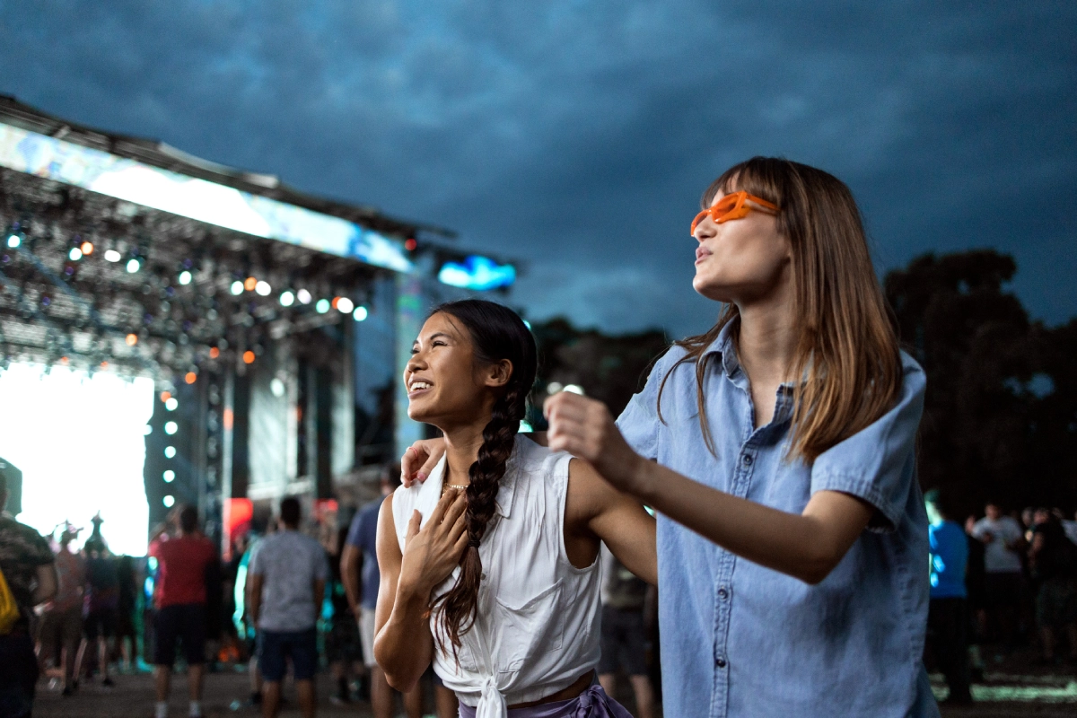 Duas amigas curtindo um festival de música durante o início da noite.