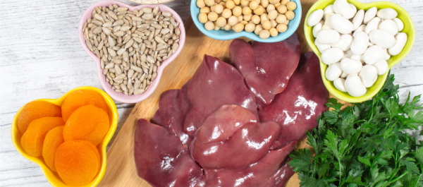 Detalhe de mesa, em vista superior, com diversos alimentos ricos em ferro, como lentilhas, fígado etc.