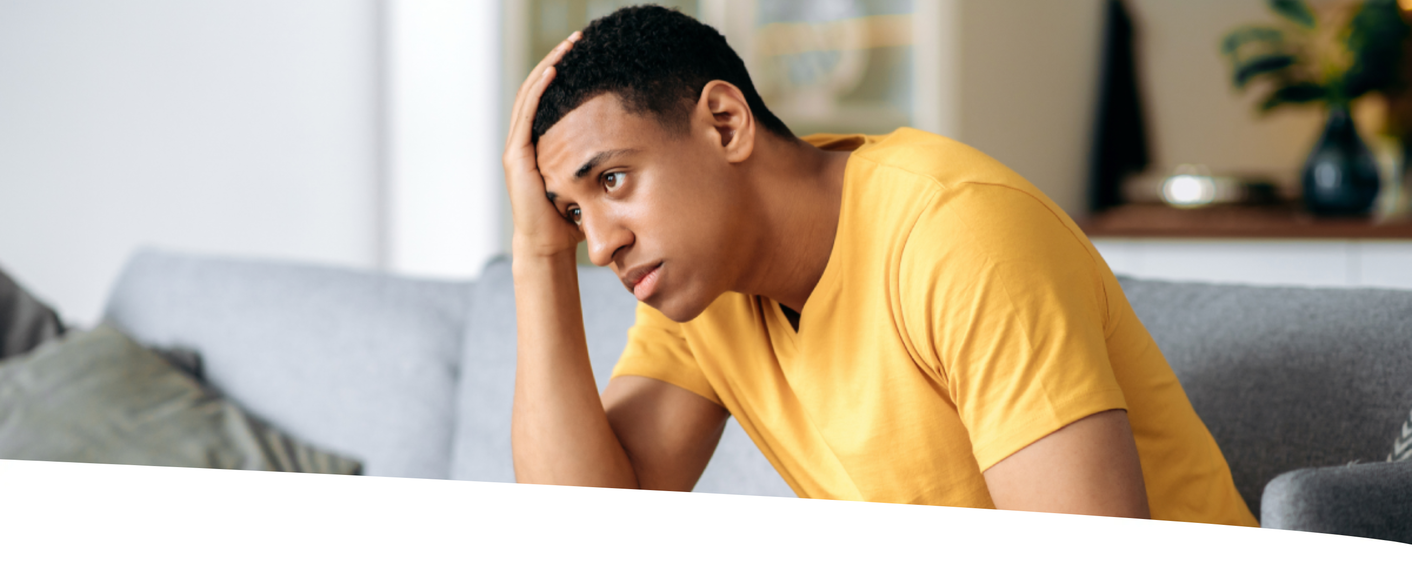 Homem sentado, com mão na cabeça e semblante preocupado