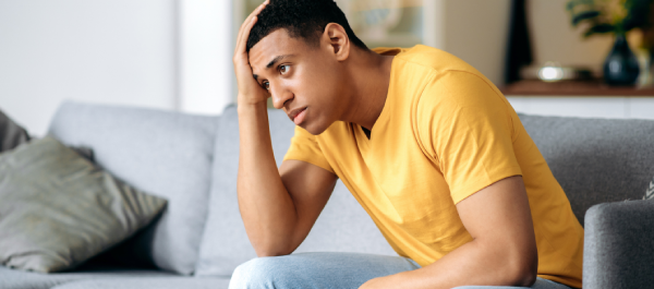 Homem sentado, com mão na cabeça e semblante preocupado