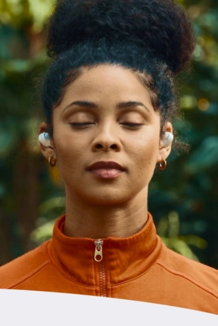 Rosto e torso de uma mulher com os olhos fechados, meditando pacificamente.