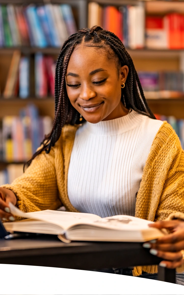 Mulher trabalhando no computador enquanto faz anotações, representando foco, energia e produtividade no dia a dia.