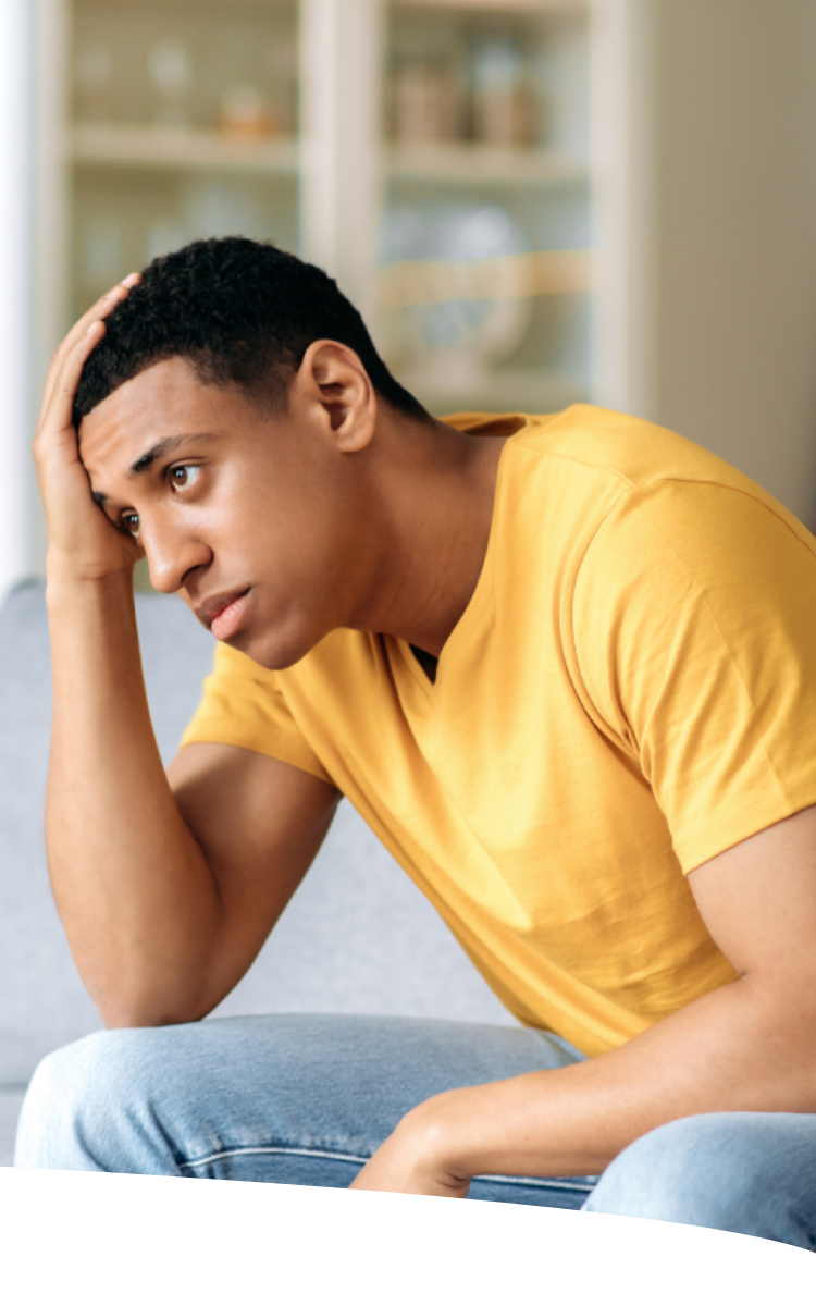 Homem sentado, com mão na cabeça e semblante preocupado