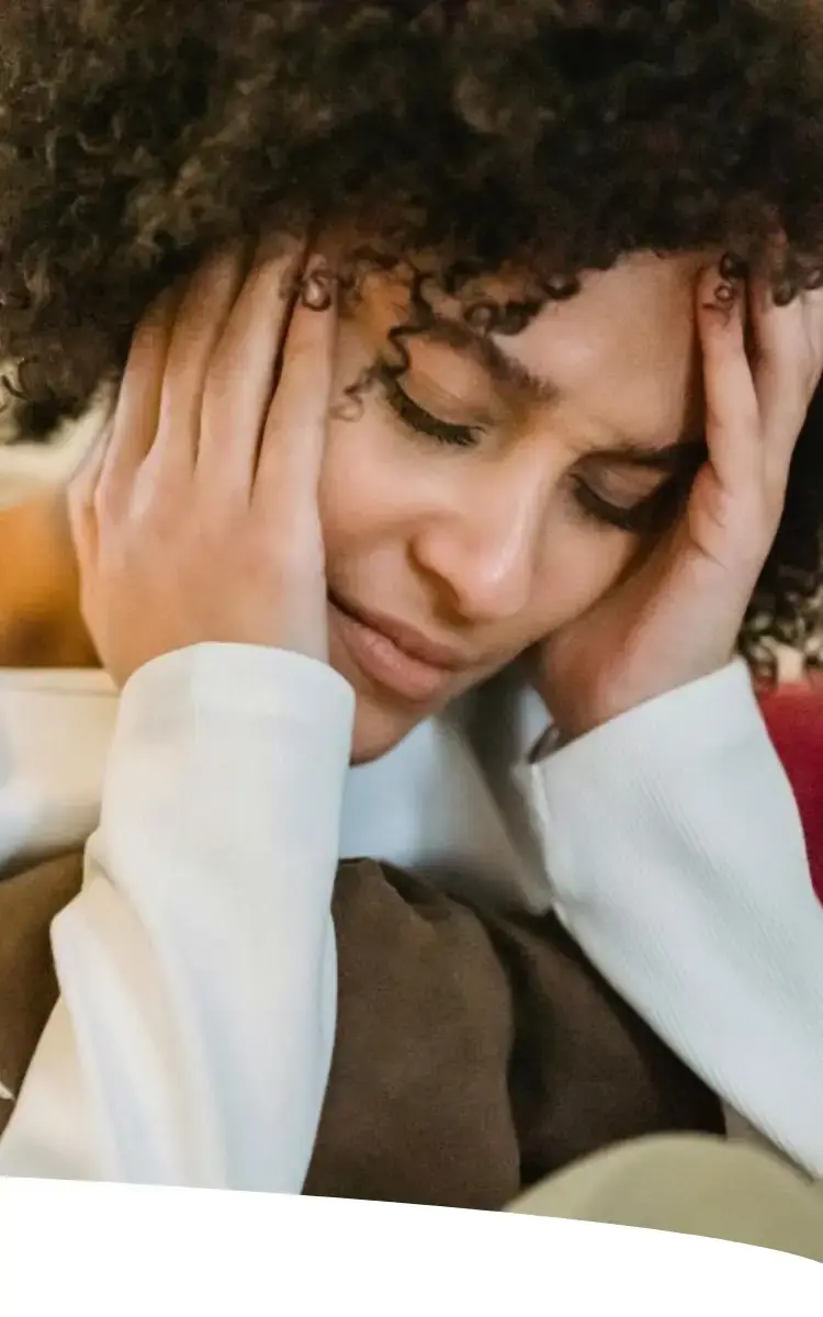 Mulher com dor de cabeça e semblante de desconforto, representando sintomas de TPM