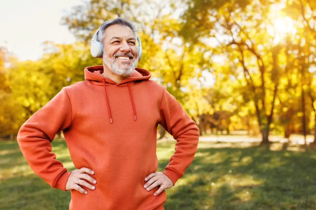 Homem sorridente com fone de ouvido no parque com traje de ginástica