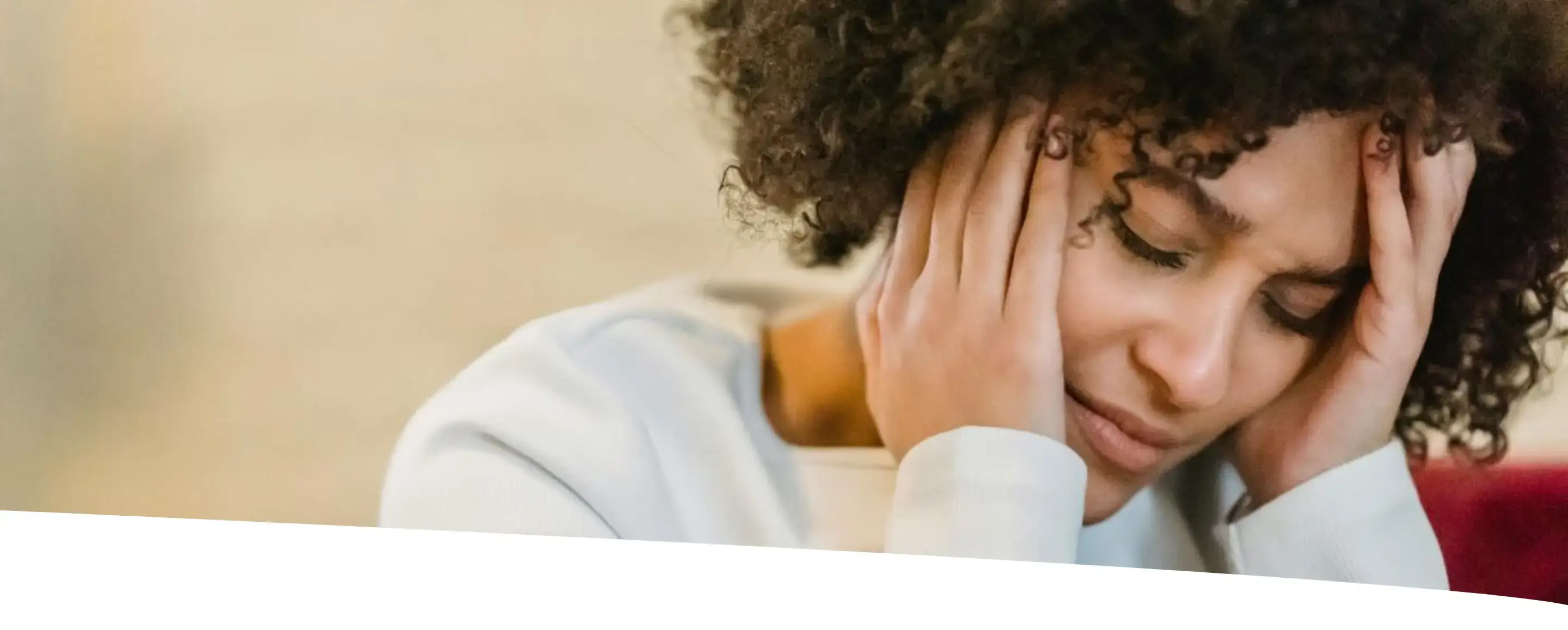 Mulher com dor de cabeça e semblante de desconforto, representando sintomas de TPM