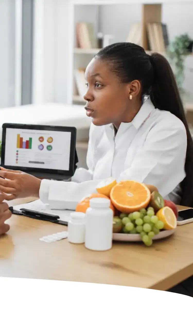 Homem conversando com sua nutricionista. Sobre a mesa, vemos alimentos frescos e suplementos.