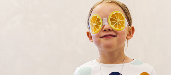 Menina usando uma máscara divertido em formato de rodelas de laranja