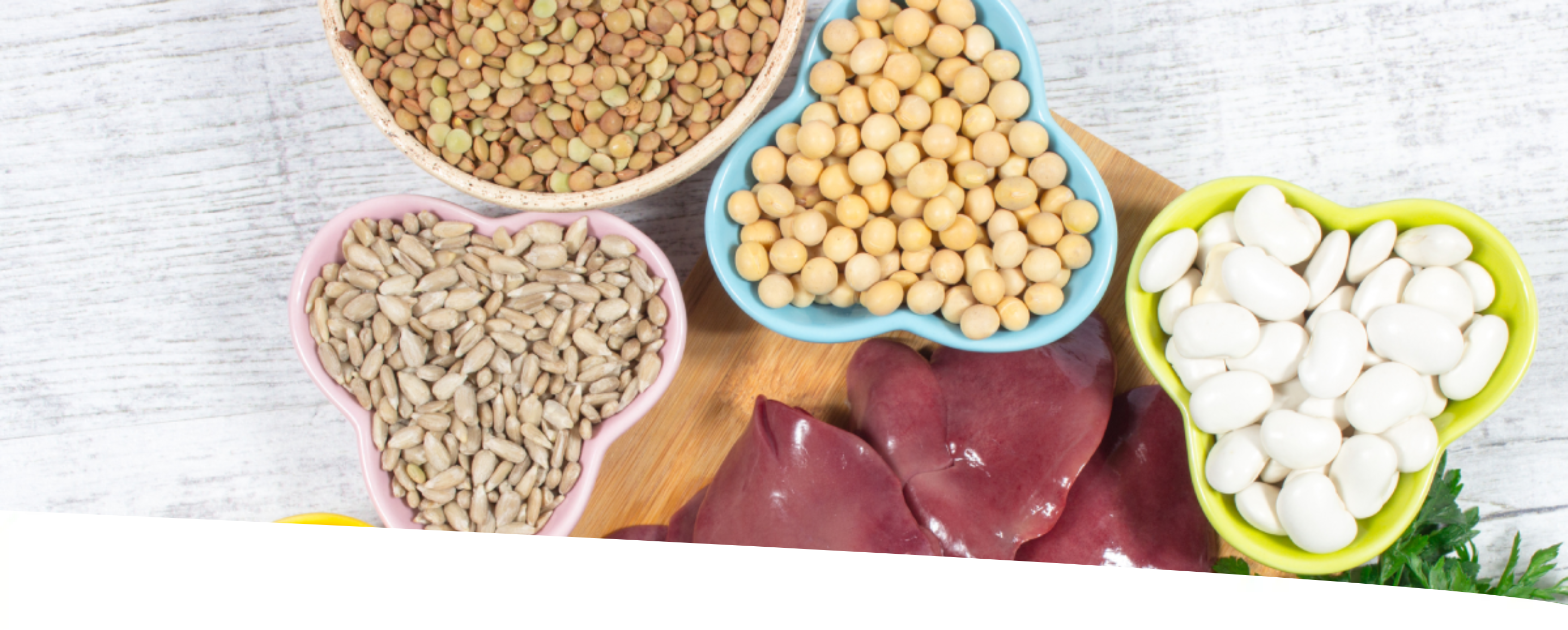 Detalhe de mesa, em vista superior, com diversos alimentos ricos em ferro, como lentilhas, fígado etc.