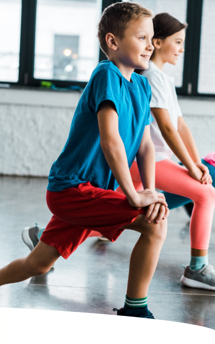Quatro crianças fazendo alongamento em uma quadra de academia.
