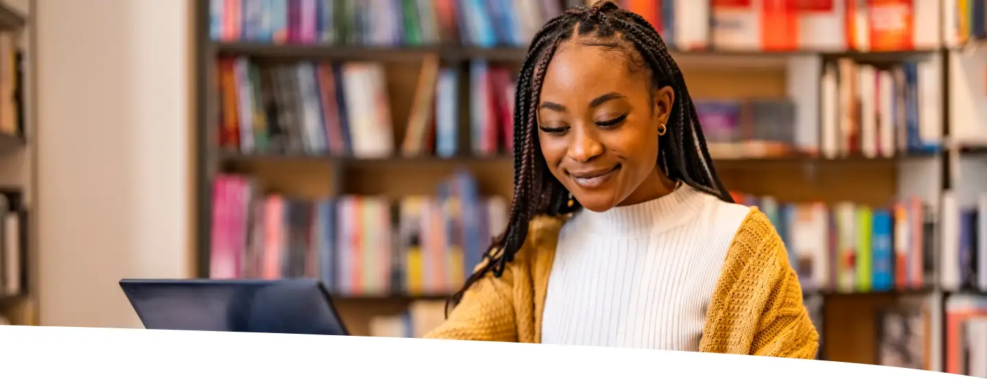 Mulher trabalhando no computador enquanto faz anotações, representando foco, energia e produtividade no dia a dia.